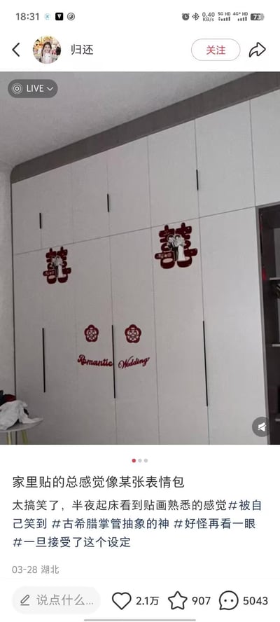 这是一张短视频平台的直播画面截图，画面主体是卧室里的白色大型衣柜，柜门贴着两对婚庆用的红色喜字贴，喜字中间的卡通新人图案意外撞脸某款表情包，给人熟悉又搞笑的感觉。发布者配文自嘲，称半夜起床看到贴画会觉得莫名熟悉，还带上了#被自己笑到 #古希腊掌管抽象的神 等趣味话题标签，整体氛围轻松搞笑，充满生活趣味。没有双关、谐音梗，完全是图案撞脸带来的笑点。