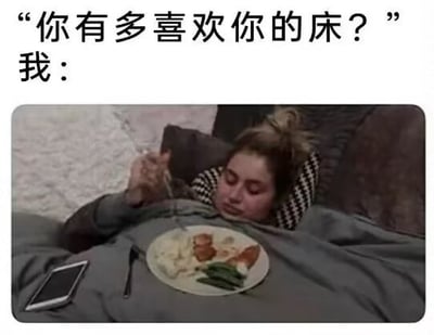 图片上方配有文字“你有多喜欢你的床？”和“我：”，下方是一张真人照片：一名女性躺在床上，盖着灰色毯子，头枕在深色枕头上，正用叉子叉起盘子里的食物（包含肉类、蔬菜和米饭），旁边放着一部手机。通过将日常活动（吃饭）转移到床上的场景，幽默地表达了对床的极度喜爱和依赖，引发观众共鸣。