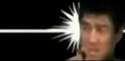 这张图以纯黑色为背景，画面右侧是一张模糊的男性人脸，一道水平的白色强光从画面左侧向右射出，在男性人脸的左侧位置炸开呈放射状的亮白色光斑，视觉效果类似强光射穿人脸，整体观感怪异离奇，充满迷惑感。