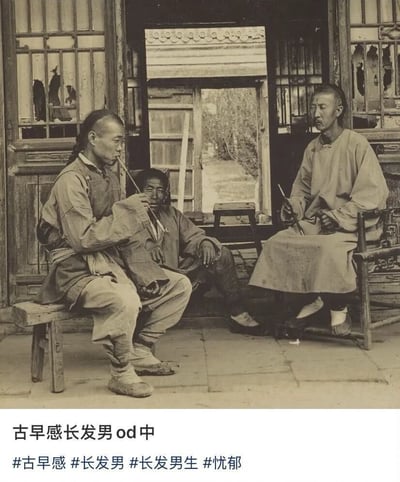 一张黑白历史照片，画面中有三位身着传统服饰的男性（疑似清代），坐在带有格子窗的木质建筑前。左侧男子手持烟斗正在吸食，中间男子侧身而坐，右侧男子端坐于椅上，三人神情略带忧郁。照片底部添加了现代文字“古早感长发男 od中”及 hashtags“#古早感 #长发男 #长发男生 #忧郁”，通过历史影像与当代网络用语的结合制造反差笑点，“od中”可能为“着迷中”的缩写，表示对这种复古风格长发男性的喜爱。
