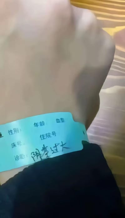 这张图拍摄了佩戴在人体腹部的医院住院识别腕带，腕带的诊断栏被手写填写了“阴茎过大”这一荒诞离谱的内容，其余如性别、年龄、血型、床号、住院号等常规信息栏位均为空白。正式的医院腕带与毫无逻辑的恶搞诊断形成强烈反差，制造出滑稽搞笑的效果，是网友创作的趣味梗图，通过荒诞设定博人一笑，属于网络恶搞类内容。