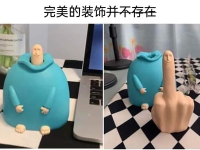 这是一张左右拼接的对比静态图，展示了一款具有反差感的搞怪桌面摆件：左侧画面中，蓝身体、小短手短脚的卡通摆件安静摆放在黑白格桌面上，旁边搭配笔记本电脑，头部是带微笑的人形短柱，看起来是温和可爱的桌面装饰；右侧画面则揭晓了它的“真面目”，摆件的头部可以取出，取出后是一个带着微笑表情的竖中指手势，蓝色身体部分则如同空外套般放置在一旁。图片顶部配有文字“完美的装饰并不存在”，通过这种视觉反差制造出搞笑、搞怪的效果，调侃了看似完美实际有“反转”的物品。