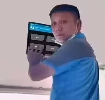 图片中一名身穿蓝色衬衫的男子，侧身站立，右手持一个带有屏幕和按钮的控制设备，设备屏幕显示部分内容，男子表情专注，似乎在操作该设备。背景为浅色，较为简洁，无明显复杂环境元素。