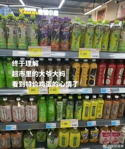 超市货架上整齐摆放着多种瓶装饮料，包括绿茶、冰红茶、青梅绿茶等，所有饮料的黄色价格标签均显示1.00元。图片中间叠加白色文字：“终于理解超市里的大爷大妈看到特价鸡蛋的心情了”，幽默地表达了普通人遇到超低价促销时与长辈产生的共鸣。右下角有水印“@娱闻蜀黍”。