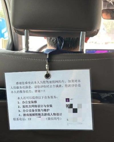 图片拍摄于网约车后座，展示了挂在座椅靠背上的透明塑料牌广告牌。牌上文字首先感谢乘客乘坐并恳请给予满意评价，称评价是服务动力；随后列出司机可提供的额外业务：办公室装修、监控及网络设计安装、办公设备安装维护、游戏视频剪辑及人物设计，并附有部分模糊的联系电话（微信同号）。前方可见司机驾驶车辆的后脑勺，整体场景真实反映了网约车司机为增加收入拓展多技能副业的现象。