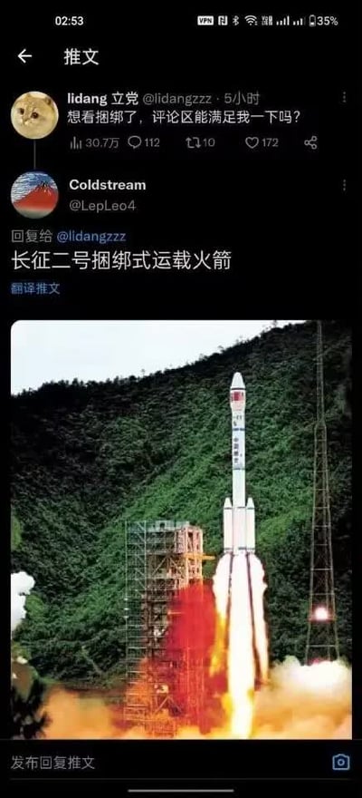 这是一张X（原推特）平台的推文评论界面截图，上方是用户lidang立党发布的推文，内容为“想看捆绑了，评论区能满足我一下吗？”，下方是用户Coldstream对该推文的回复，文字内容为“长征二号捆绑式运载火箭”，并附带一张长征二号捆绑式运载火箭点火发射的实拍图片，图片中火箭底部喷射出火焰和烟雾，背景是覆盖着茂密绿植的山体与发射塔架，回复者利用“捆绑”的字面含义玩谐音梗，回应该楼主的诉求。
