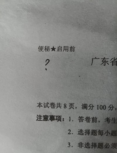 一张广东省的考试试卷照片，试卷顶部本应印有'保密★启用前'的字样，却被误印为'便秘★启用前'，引发网友爆笑。试卷下方显示'本试卷共8页，满分100分'及注意事项，包括答卷前考生需注意的事项、选择题和非选择题的答题要求。整体画面为纸质文档的原始拍摄，文字清晰可见，核心笑点在于官方文件出现低级文字错误。