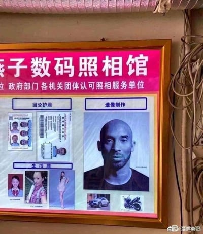 这是燕子数码照相馆的宣传灯箱，灯箱标注该店是政府部门各机关团体认可的照相服务单位，展示了三项业务：因公护照、生活照、遗像制作。其中遗像制作板块使用了已故NBA球星科比·布莱恩特的正面半身照作为示例，这种将知名离世人物的照片用作遗像模板的搭配，产生了强烈的违和感与搞笑效果，让看到的人既觉得尴尬又忍不住发笑。