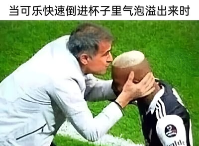 图片展示了一个足球教练正低头靠近一名光头足球运动员的场景，教练双手扶着运动员的头部，两人距离极近。图片上方配有文字"当可乐快速倒进杯子里气泡溢出来时"，通过视觉比喻的方式，将运动员的光头和可乐倒入杯子时溢出的泡沫联系起来，形成幽默效果。