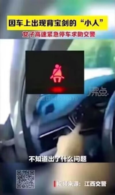 图片为竖屏视频截图，内容展示一辆汽车的驾驶座内部，一只手正指向仪表盘区域。画面上方有黄色背景黑色文字横幅写着“因车上出现背宝剑的‘小人’”，其下为红色文字“女子高速紧急停车求助交警”。中间嵌入一个红色的汽车安全带警示灯图标（显示一个系安全带的人形图案，被误解为“背宝剑的小人”）。底部有白色文字“不知道出了什么问题”，右下角标注“视频来源：江西交警”，中部偏左有“沙雕群546370479”的水印及一个二维码。整体内容源于一起因车主误解汽车警示灯图标而引发的高速紧急停车事件，具有搞笑和科普交通安全知识的双重性质。