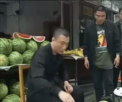 动图内容为电视剧《征服》的经典桥段：孙红雷饰演的刘华强来到水果摊前，弯腰抬手向摊上的西瓜拍去，受力的西瓜瞬间裂开一道长缝，一旁的水果摊主站在原地看着刘华强，氛围充满压迫感，对应网友熟知的“这瓜保熟吗”经典梗，常用来表达对事物真实性的质疑，带有挑衅、调侃的情绪。