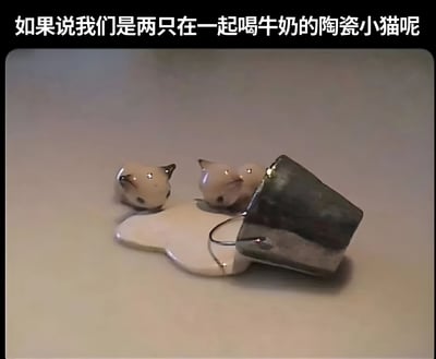 图片上方有一行白色文字“如果说我们是两只在一起喝牛奶的陶瓷小猫呢”，下方展示了两只浅色陶瓷小猫摆件。小猫有着黑色的耳朵和亮晶晶的眼睛，正趴在一片形似打翻牛奶的白色底座上，旁边还有一个倾倒的灰色小方块（疑似牛奶盒），整体画面呈现出温馨治愈的可爱氛围。