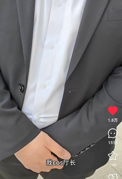图片中展示一位身着深色西装与白色衬衫的人士，双手交叉置于身前。右侧有社交媒体互动数据：红色爱心图标旁显示“1.8万”（点赞数），对话气泡图标旁显示“1514”（评论数），星形图标旁显示“748”（收藏数）。图片底部有文字“我cos厅长”，整体呈现出一种cosplay模仿部门领导的幽默场景，结合来源标题“那那确实超过98%的二次元了(x”，可能暗含对二次元模仿程度的调侃。