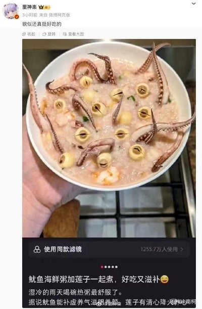 这是微博用户“里神楽”发布的一条创意美食内容，展示了一碗鱿鱼莲子海鲜粥。粥中的鱿鱼须和莲子的位置形成了趣味视觉错位效果，莲子如同章鱼的眼睛，鱿鱼须像章鱼的触手，看起来仿佛是一只章鱼“待在”粥里，营造出搞笑又新奇的视觉体验。博主配文表示这款粥好吃又滋补，湿冷的雨天喝热粥非常舒服，还介绍了鱿鱼和莲子的滋补功效，同时博主自己也评论“貌似还真挺好吃的”。该内容使用了一款已有1255.7万人使用的微博同款滤镜，整体风格治愈又有趣，适合在雨天分享暖心美食内容。