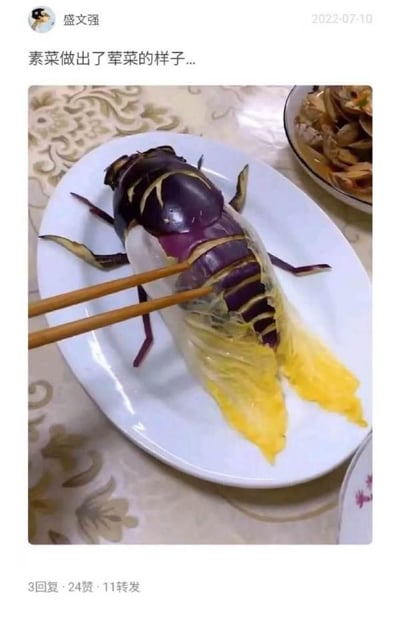 这是一张微博用户发布的社交媒体截图，展示了一道极具创意的仿荤素菜。料理制作者用紫色茄子作为主体，通过切割塑形搭配白菜叶，将素菜摆出了类似甲壳类海鲜的逼真荤菜外形，筷子正夹在这道创意料理的身体部位。截图上方配文“素菜做出了荤菜的样子...”，点明了这道菜的趣味核心，背景中还能看到一盘真实的蛤蜊类荤菜，与创意素菜形成对比，更凸显其巧思。该发布来自用户“盛文强”，发布时间为2022年7月10日，获得了3条回复、24个赞和11次转发，这类创意料理内容很容易引发网友对美食创意的讨论。