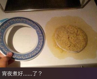 这张图呈现了一个做饭翻车的搞笑日常场景：一只手拿着只剩蓝白花纹外圈的瓷盘，台面上留下了一个和盘底形状完全贴合的饭团，饭团周围还残留着溢出的浅黄色汤汁。图片下方配文“宵夜煮好……了？”，充满了无奈又好笑的氛围——原本准备的宵夜米饭，完全粘在了盘子底部，拿起盘子后只留下了形状规整的饭团，期待的宵夜变成了这样的窘境，让人哭笑不得，用视觉上的错位和真实的翻车经历制造出搞笑效果。
