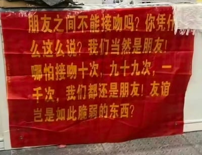 这是一张红底黄字的趣味横幅，上面印着一连串充满“嘴硬”感的发言：质问“朋友之间不能接吻吗”，强调哪怕接吻十次、九十九次甚至上千次，两人都还是朋友，宣称友谊不会如此脆弱。用夸张的话术玩“友达以上，恋人未满”的暧昧梗，搞笑又傲娇，精准戳中那种明明有暧昧互动却嘴硬不肯承认的状态。