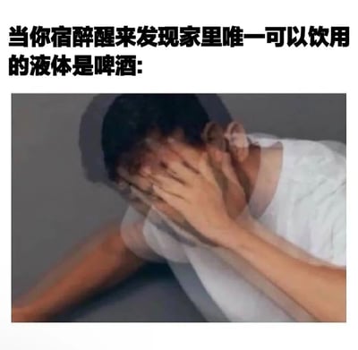 图片上方有黑色加粗文字‘当你宿醉醒来发现家里唯一可以饮用的液体是啤酒:’，下方是一张真人照片。照片中一名穿着白色上衣的男子趴在桌上，双手紧紧捂住脸，身体姿态呈现出明显的疲惫与崩溃感，生动展现了宿醉后极度口渴却发现家中只有啤酒可饮时的尴尬又绝望的场景。