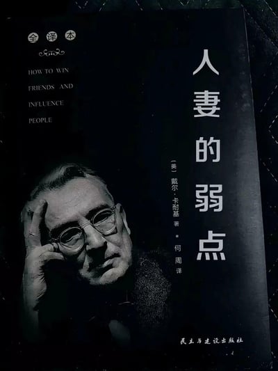 这是一张经过P图改编的恶搞书籍封面，原版是戴尔·卡耐基的经典著作《人性的弱点》（英文原名HOW TO WIN FRIENDS AND INFLUENCE PEOPLE），被修改为《人妻的弱点》，保留了原作者、译者信息和出版社信息，以及卡耐基的肖像，通过谐音梗制造反差搞笑效果。
这里使用了谐音梗，将原书名《人性的弱点》中的“人性”替换为“人妻”，形成荒诞的恶搞效果。