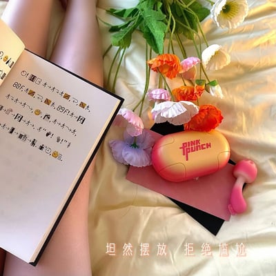 床上铺着浅色床单，左侧是打开的笔记本，页面上有手写的文字和各类符号（如箭头、表情图案），旁边露出人物的腿部；右侧摆放着一束色彩鲜艳的花束，包含橙色、粉色、白色和紫色的罂粟花，花束下方是一个渐变橙粉配色的“PINK PUNCH”收纳盒，盒旁还有一个粉色蘑菇造型的小物件。图片底部配有文字“坦然摆放 拒绝尴尬”，整体营造出轻松自然、无拘无束的生活氛围。