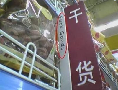 这是一张超市内的实拍照片，画面聚焦在干货区域的标识牌上，标识牌上的中文为“干货”，但对应的英文翻译却错误地写成了带有粗俗冒犯性的“Fuck Goods”，与“干货”的正确英文表述（如Dried Goods）完全不符，形成了尴尬又搞笑的乌龙场景。
笑点说明：翻译失误将食品类的“干货”错误翻译成了脏话相关的表述，反差感拉满，引发吐槽。