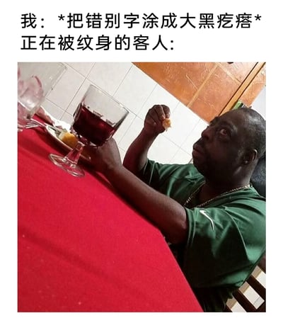这是一张利用视觉错位效果制作的搞笑梗图，上方文字设定了纹身场景：纹身师将纹身上的错别字涂成大黑疙瘩，而正在被纹身的客人看到这个补救结果后，对应下方的视觉错位照片——照片中的黑人男性因拍摄角度问题，手与酒杯的位置组合看起来像是他的手臂上有一块大黑块，同时他瞪大双眼，露出震惊、不敢置信的表情，完美契合客人看到自己纹身上被涂成大黑疙瘩时的崩溃、错愕心态，通过视觉错位和场景结合，制造出荒诞搞笑的效果，调侃纹身出错补救的尴尬场景。