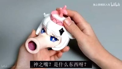 图片展示了一双手正在拿着一个玩具手办的头部特写。这个手办有着白色的头发、蓝色的眼睛和一个夸张巨大的张开的嘴巴，头上戴着一个粉色的皇冠，皇冠顶部有一个十字形装饰。手办表情看起来有些疑惑。图片底部有一行文字："神之嘴？是什么东西呀？"，右上角有"独上西楼跃入沟 bilibili"的水印，左下角也有bilibili相关的水印信息。这张图片看起来像是某个视频的截图，展示了一个设计夸张有趣的玩具手办。