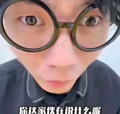 图片为近距离面部特写，聚焦于一位戴圆形黑框眼镜人士的上半脸，其双眼睁大、眼神略带迷茫，眉头微蹙，表情透露出明显的困惑。人物穿着深色带白色线条装饰的上衣，背景为简洁的浅色，无其他干扰元素。图片底部有白色加粗文字“你这家伙在说什么呢”，直接点明画面传达的不解情绪，整体构图突出人物表情与文字的呼应。