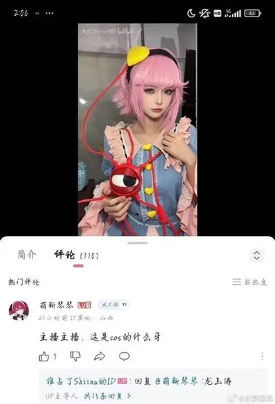 本图是一张B站二次元Cosplay评论区互动梗图。画面中人物身着粉色假发、蓝色和粉红色相间的cos服饰，手持标志性第三只眼道具，因红色外形酷似龙虾，被网友在评论区神评为“龙虾精”，形成强烈对比和玩梗效果。整体风格幽默，充分展现了ACG圈和网友的调侃文化。“龙虾精”属于谐音梗和恶搞吐槽的典型二次元圈文化现象。