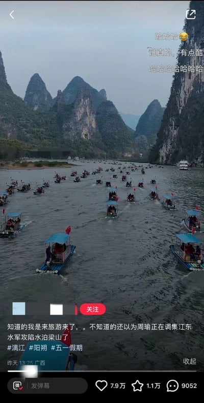 五一假期期间阳朔漓江上的旅游场景，江面上密密麻麻布满了蓝色顶棚的游船，远处是典型的喀斯特地貌山峰。配文幽默地将游船密集的场景调侃为“周瑜正在调集江东水军攻陷水泊梁山”，用历史典故夸张形容假期旅游的火爆场面。