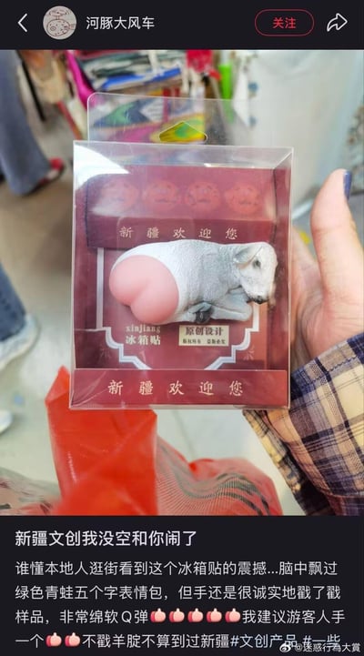 这是一张微博平台的分享截图，展示了一款极具反差感的新疆主题文创冰箱贴：造型为一只趴着的绵羊，重点突出了绵软Q弹的粉色羊屁股，包装上印有「新疆欢迎您」的字样。博主作为本地人，分享了逛街看到这款冰箱贴的震撼感受，调侃自己脑中飘过「绿色青蛙」表情包，却忍不住上手戳了戳样品，还玩梗称「不戳羊腚不算到过新疆」，搞笑推荐游客人手一个，充满趣味的吐槽感。