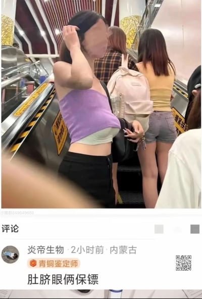 图片展示了在自动扶梯上的场景，一位穿着紫色抹胸上衣和黑色裤子的女性站在前景，她的脸部被模糊处理。她的穿搭露出了部分腹部，引发了评论区的幽默回应。图片下方显示了一条评论：'肚脐眼俩保镖'，以幽默的方式描述了她的服装特点。
