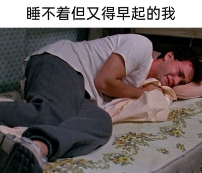 这是一张经过二次创作的文字加注类影视截图，顶部配有文字“睡不着但又得早起的我”。图中来自电影《飞越疯人院》的角色蜷缩在床上，眉头紧皱，脸部挤在枕头上，表情痛苦又烦躁，身体姿态紧绷焦虑，生动地将明明需要睡眠却无法入眠，同时还要面对早起压力的煎熬、烦躁又无助的情绪具象化，精准戳中了很多人在生活中面临这种处境时的内心感受，极易引发共鸣。