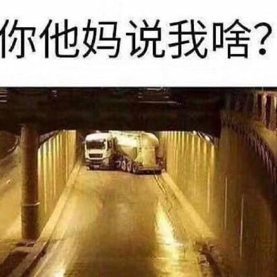 这是一张趣味视觉错位梗图，上方配有愤怒的质问文字“你他妈说我啥？”，下方是在隧道中行驶的水泥罐车。由于视觉错位效果，水泥罐与车头的组合形态看起来像一个皱着眉头、瞪着眼睛的愤怒人脸，配文与画面完美呼应，仿佛是这个“人脸”在发出愤怒的质问，营造出荒诞搞笑的氛围。

这张图利用视觉错位的创意，将车辆形态联想成人的表情，通过配文强化情绪，成为表达愤怒、不满情绪或玩梗的素材。
