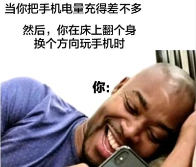 这是一张贴合日常的搞笑梗图，采用图文混排的形式，上方用文字描述了一个常见的生活场景：当手机电量充得差不多后，在床上翻身换个方向玩手机。下方配了一张光头男子的实拍照片，男子侧躺在床上，一只手撑着头，脸上露出十分满足惬意的笑容，正专注地看着手机，照片上标注了“你:”，精准地将文字描述的场景和人物的状态结合起来，放大了这种日常小确幸的快乐，让有类似经历的人产生强烈共鸣，是用来调侃宅家玩手机日常的趣味表情包。