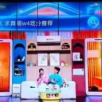 这是一张抖音平台的直播画面截图，画面中一男一女两位真人主播坐在布置温馨的室内沙发上，背景是带有置物架的家居风格场景。画面上方的蓝色区域显示文字「求舞萌w4吃分推荐」，右上角带有抖音的平台标识。整体场景是主播在直播过程中，向观众征集音乐节奏游戏《舞萌》中w4难度级别下的「吃分」（获取高分）技巧推荐，氛围轻松友好。