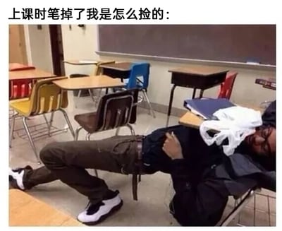 这是一张趣味实拍梗图，图片上方配有中文文案“上课时笔掉了我是怎么捡的：”，图中场景为一间摆放着多组彩色课桌椅的教室。一名戴眼镜的男生以极其夸张的姿势趴在课桌上，他的下半身滑到了地面，双腿弯曲，整个身体呈现出一种费力又滑稽的姿态，用这种夸张的方式来还原学生上课时，既不想起身打扰课堂秩序，又要捡起掉落的笔的窘迫小心思，画面充满搞笑感，精准戳中很多学生的校园生活共鸣点。