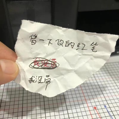 这是一张充满反差感的趣味手写小纸条：纸条上方写着“借一下你的红笔”，中间先用红笔写下“我没带”，随后又被黑笔圈画起来，最后再用黑笔重新写了一遍“我没带”。用红笔书写“没带红笔”的行为形成了强烈的自我矛盾，制造出搞笑的“打脸”效果，充满了日常小玩笑的趣味感。