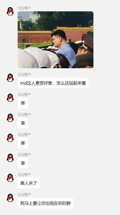 这是一张QQ聊天记录截图，展示了一群用户对一张照片的讨论。照片中显示了一群人在户外聚集，背景有红色墙壁和黄色屋顶的古建筑，看起来像是一处旅游景点。一位用户评论"md这人素质好差，怎么还站起来看"，似乎在抱怨照片中有人站起来挡住了其他人的视线。其他用户则用"草"（网络用语，表示惊讶或好笑）回应，最后有人说"高人来了"和"我马上要让你出现在别的群"，暗示要将这个截图分享到其他群组。