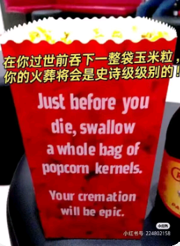 这是一张P图改编的顶配底文图，采用图文混排的竖屏手机格式，主体是带有白色边框的红色爆米花桶样式载体，上面印有中英文对照的荒诞搞笑标语。中文内容为“在你过世前吞下一整袋玉米粒，你的火葬将会是史诗级别的！”，英文内容为“Just before you die, swallow a whole bag of popcorn kernels. Your cremation will be epic.”，该内容利用玉米粒遇高温会膨胀成爆米花的特性，开了一个关于火葬的脑洞玩笑，风格幽默荒诞，旨在通过离谱的创意博人一笑。图片右下角带有小红书平台的水印，标注了对应的小红书号，整体构图清晰，属于标语/口号类的搞笑创意图。