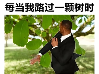 图片上方有黑色大字标题'每当我路过一颗树时'，下方是一名穿着黑色西装、白色衬衫和黑色领带的男子，侧身站在茂密的绿色树叶中，右手抬起似乎在触碰或拨开树叶，背景是户外自然场景，有绿色草地和树木。男子的正式着装与他与树叶互动的略显滑稽的动作形成反差，营造出幽默搞笑的效果。