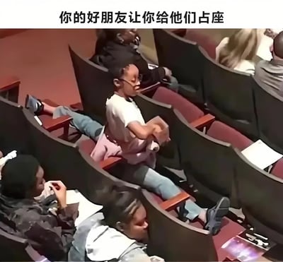 图片展示了一个阶梯教室场景，红色座椅排列整齐，中间一名穿着白色上衣、蓝色牛仔裤的人将双腿大大张开，同时占据了左右多个座位。图片顶部配有文字'你的好朋友让你给他们占座'，幽默夸张地表现了为朋友占座时的投入状态，让人会心一笑。