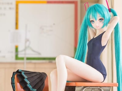 这是一张初音未来手办的原创实拍静态图，手办拥有标志性的青蓝色双马尾长发，身着深蓝色连体泳衣款式的服装，正坐在教室的课桌上，双手举至脑后整理头发，姿态放松自然。在旁边的椅背上搭着一条带有青蓝色装饰边的黑色百褶裙，背景是模糊的教室白板，整体场景模拟了校园课后或准备更换服装的氛围，手办造型精致，完美还原了初音未来的软萌可爱形象。