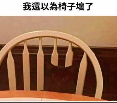 这是一张利用视觉错位制造趣味效果的静态图片，画面主体是浅色木质椅背的局部，背景是深色墙面上的浅色装饰条，这些装饰条恰好和椅背的竖条在视觉上重合，看起来仿佛椅背的两根竖条“断裂”了。图片顶部配有文字“我还以为椅子坏了”，精准点出了这种视觉错觉带来的第一感受，让观看者产生椅子损坏的误判，实际是生活场景中巧合形成的趣味视觉现象。