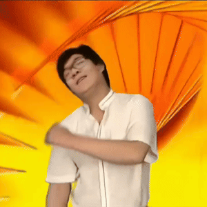 这是一张魔性搞笑的动态表情包，画面中的人物是韩国演员崔成国，也就是网友熟知的“金馆长”。他闭着眼睛，面部表情夸张扭曲，一只手在自己的胳膊上来回蹭动，背景是橙黄色的放射状图案，整体风格滑稽搞怪，常被用于社交聊天中表达尴尬、无语，或是用来缓解当下的尴尬氛围，图中没有双关、谐音梗等内容。