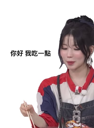 这是一张社交网络流行的表情包。画面中有一位女性穿着综艺服饰，手拿筷子，正在准备吃东西，左侧用黑体字号写着“你好 我吃一点”。这类图片通常用来表达想要分到一点食物的俏皮心情，或在聊天时主动索取分享。语气亲切、撒娇，十分适合用在朋友互动、饭桌场景。目前本图没有明显双关、谐音梗，但常被用来半开玩笑地表达请求分东西的情绪。