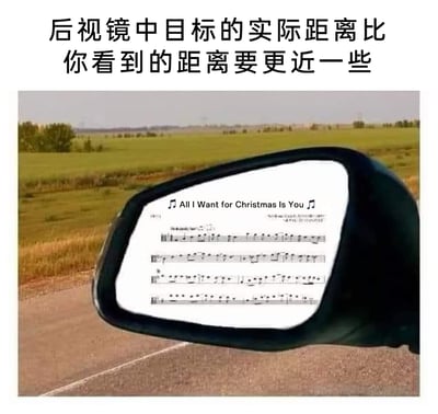 这是一张经过合成改编的趣味网络梗图，画面上方配有驾驶领域的安全提示文字“后视镜中目标的实际距离比你看到的距离要更近一些”，图中主体为汽车的侧后视镜，但镜中并未呈现常规的后方道路或车辆景象，而是被替换成了玛丽亚·凯莉演唱的经典圣诞流行歌曲《All I Want for Christmas Is You》的乐谱，同时标注了歌曲名称与音符符号。该图巧妙结合了后视镜“实际距离更近”的提示逻辑，以及这首歌曲在圣诞季极高的传播度与“无处不在”的存在感，制造出“这首歌仿佛离自己很近、时刻环绕”的幽默效果，属于典型的网络迷因创作，能引发对该歌曲有共鸣的网友的会心一笑。