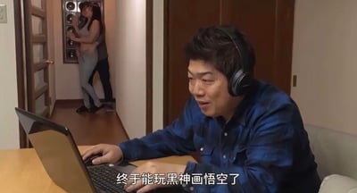 图中前景是一位戴着耳机的男士，正兴奋地坐在桌前操作笔记本电脑，眼神专注在屏幕上，配文写着「终于能玩黑神画悟空了」，看起来完全沉浸在游戏的快乐中。而背景的走廊里，有一男一女正在进行亲密互动，形成了强烈的反差感，营造出搞笑又尴尬的氛围。

谐音梗说明：图中配文「黑神画悟空」是国产游戏《黑神话：悟空》的谐音写法，属于玩梗创作。