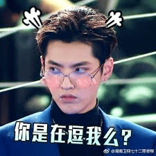 图片中是一位戴着眼镜的真人男性，头发梳理整齐，额头上方有两个类似小感叹号的装饰图案。人物脸颊带有粉色腮红，表情呈现出困惑且略带不悦的神态，侧头凝视着一侧。图片底部配有白色文字“你是在逗我么？”，整体营造出一种被调侃后的疑问与无奈情绪。