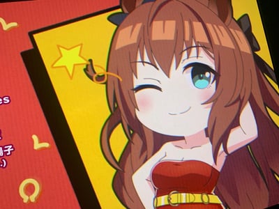 这是一张出自《赛马娘 Pretty Derby》的官方Q版角色截图，图中是角色爱丽速子，她有着标志性的棕色长发与马耳，身穿红色抹胸裙搭配黄色腰带，正单眼wink，面带微笑，一只手轻放在胸口，姿态俏皮可爱。画面背景分为黄色与红色区域，黄色区域旁有星星装饰，红色区域带有马蹄形图案与部分中文文字，整体风格活泼元气，充满二次元萌系感。